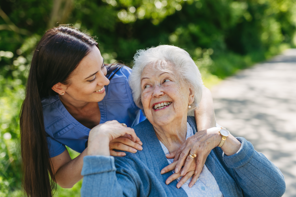 Nurse and elderly woman enjoying a warm day in nursing home, public park.